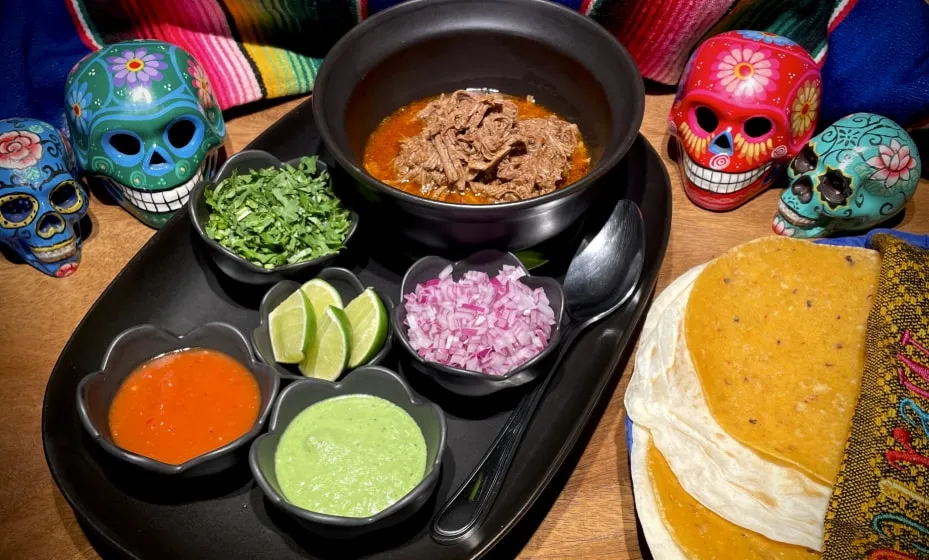 Birria beef with consommé, tortillas, lime, onion and salsas