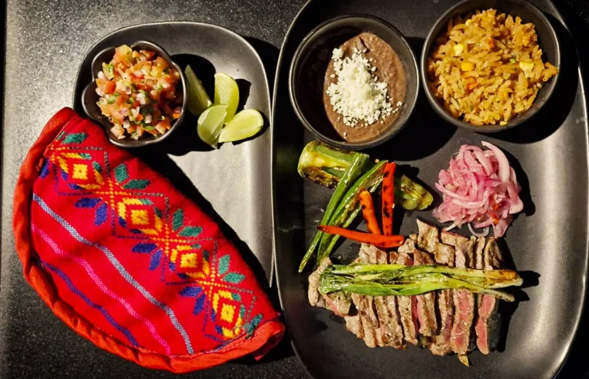 Sliced sirloin steak with grilled spring onions, beans, rice and tortillas