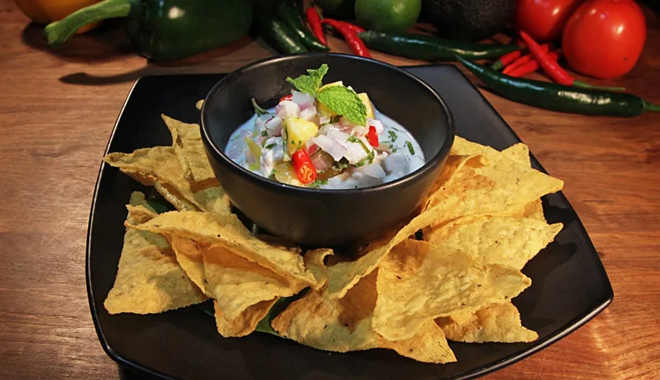 A bowl of seabass ceviche with mango, served with corn chips